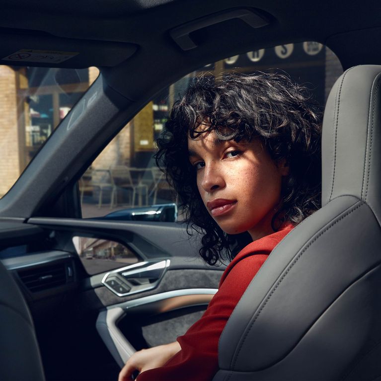 La mujer mira por encima del hombro desde el asiento del pasajero de un Audi e-tron Sportback